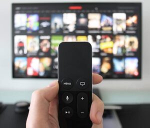 a person pointing a remote in front of a tv