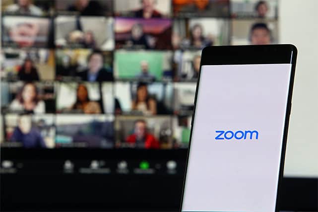 An image featuring a phone and a TV in the background that are using the Zoom application